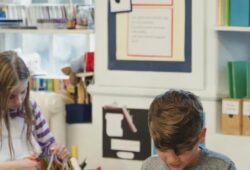 Teacher guiding students in a classroom setting, illustrating behaviorist learning through reinforcement and structured instruction.