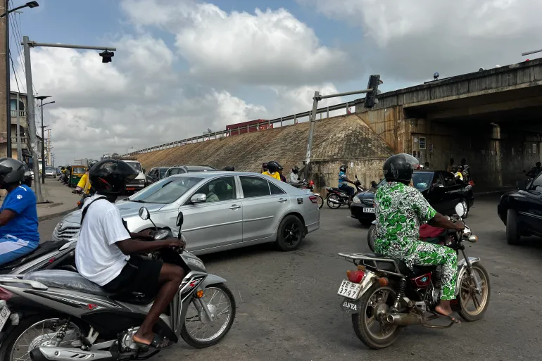 A street scene in Cotonou during reports of a coup attempt claim, with security forces and motorists visible